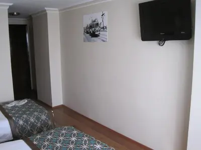 a room with a tv on the wall and a chair at Avlonya Hotel in Istanbul