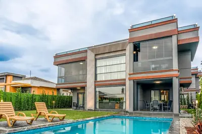 a house with a swimming pool and two lawn chairs at Andalus Villas NO ALCOHOL ALLOWED with Heated Pool in Sapanca
