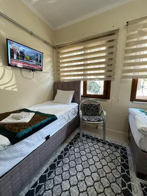 a bedroom with two beds and a tv on the wall at Apart La Mia in Istanbul