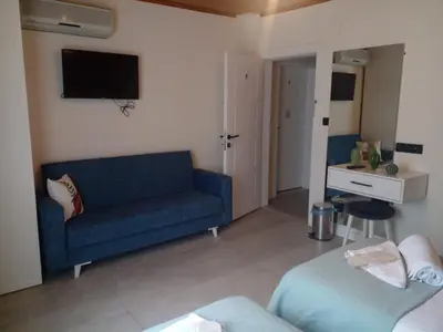 a living room with a blue couch and a tv at Villa Nora Butik Otel ve Bungalov in Bursa