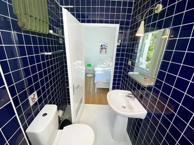 a blue tiled bathroom with a toilet and a sink at Petek Pansiyon Fenerbahce Kadikoy in Istanbul