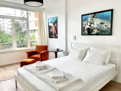 a white bedroom with a bed and a chair at Petek Pansiyon Fenerbahce Kadikoy in Istanbul