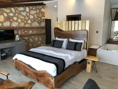 a bedroom with a large wooden bed and a tub at Masklavi in Kestel