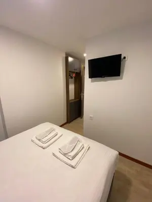 a room with a bed with white sheets and a flat screen tv at Mina Life Hotel in Istanbul