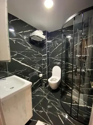 a black tiled bathroom with a toilet and a sink at Hotel Blue Ottoman in Istanbul