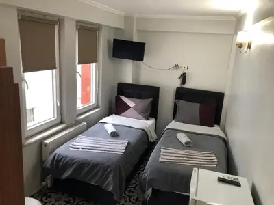 two beds in a small room with two windows at Reydel Hotel in Istanbul
