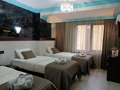 a hotel room with three beds and a chandelier at Hotel Falcon in Istanbul