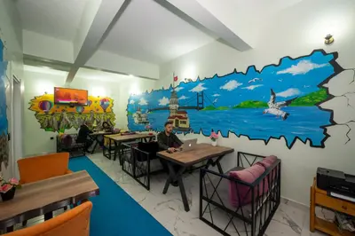 a man sitting at a table in a restaurant with a mural at XALİLA HOSTEL & CAFE, MEN's ROOM, BEST IN ISTANBUL , in Istanbul