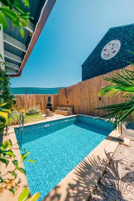 a swimming pool in front of a fence with a clock at Tree Bungalov Maşukiye in Kartepe