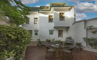 a white house with a wooden deck with a table and chairs at Villa Paradiso Hotel & Spa in Istanbul