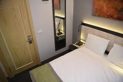 a bedroom with a bed with white sheets and a door at BEST HOTEL KADIKOY in Istanbul