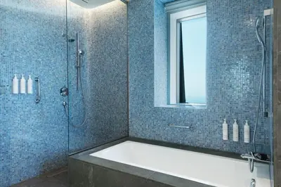 a bathroom with a tub and a shower with a mirror at Istanbul Marriott Hotel Sisli in Istanbul