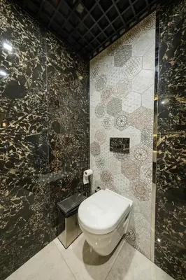 a bathroom with a toilet and a tiled wall at MQ Hotel Suites & SPA in Arnavutköy