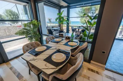 a dining room with a table and chairs and large windows at MQ Hotel Suites & SPA in Arnavutköy