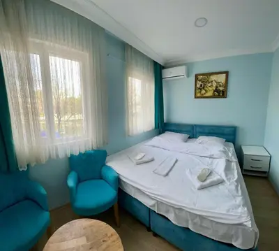 a bedroom with a bed and two blue chairs at AVRASYAQUEEN HOTEL in Istanbul