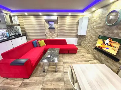 a living room with a red couch and a tv at LEVENT PALACE REZİDANS in Istanbul