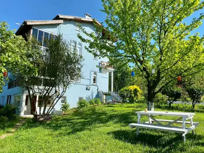 a white bench in the grass in front of a house at Maşukiye Home Suit Apart in Kartepe