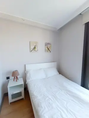 a white bedroom with a bed and a night stand at Luxury Central Fully Equipped 3BR 2BA Apartment by Siena Suites in Istanbul