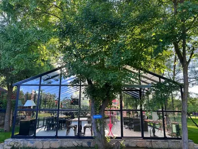 a glass pavilion with tables and chairs and a tree at Dachas Cove Hotel in Agva