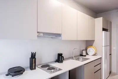 a small kitchen with white cabinets and a sink at New Inn Hotel Cadde 54 Mall in Sakarya