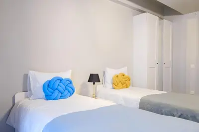two beds with blue and yellow pillows on them at New Inn Hotel Cadde 54 Mall in Sakarya