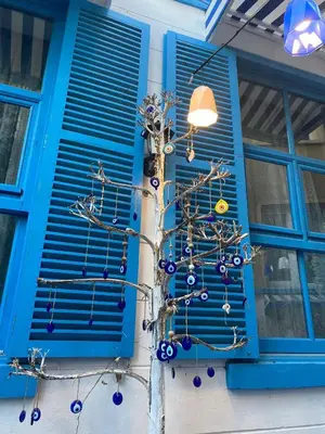 a christmas tree in front of a window with blue shutters at MAVİ PALAS HOTEL in Buyukada