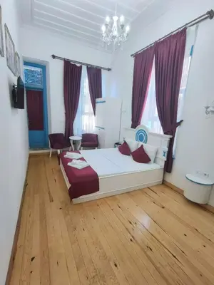 a bedroom with a white bed and wooden floors at MAVİ PALAS HOTEL in Buyukada