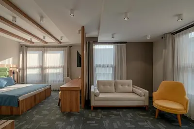 a bedroom with a bed and a chair and windows at ERTA SOYAK THERMAL OTEL in Çekirge