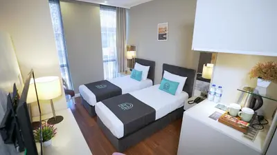 a hotel room with two beds and a television at Homey AirPort Hotel in Arnavutköy