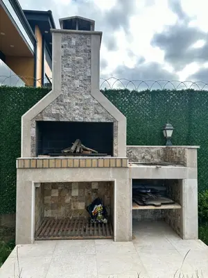 a stone fireplace in a yard next to a fence at SAPANCA ALHARRAN VILLA in Sapanca