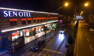 a street with cars parked in front of a store at night at Sen Otel in Sakarya
