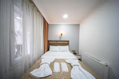 a bedroom with a bed with white sheets and a window at LAOS OTEL in Istanbul