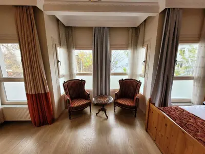 a bedroom with two chairs and a bed and windows at Masif House in Istanbul