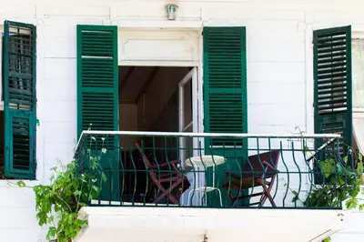 a balcony with two chairs and green shutters at No16 Ada in Adalar