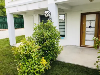 a white house with two bushes in front of a door at Sapanca Manzara Villa 2 Isıtma Havuzlu in Sapanca