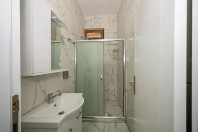 a white bathroom with a shower and a sink at XALİLA HOSTEL & CAFE LADİES ROOM in Istanbul