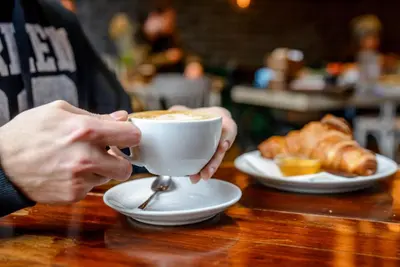 a person holding a cup of coffee on a table at Taksim Square Leon's Hotel in Istanbul