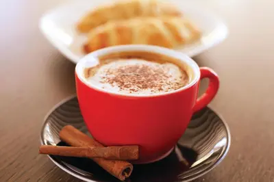 a red cup of coffee on a plate with cinnamon sticks at Tuyap Palas in Istanbul