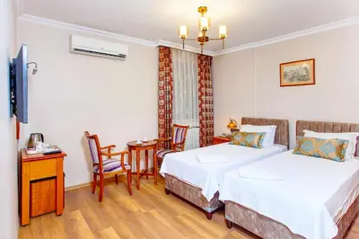 a hotel room with two beds and a table and chairs at Hotel Saba in Istanbul