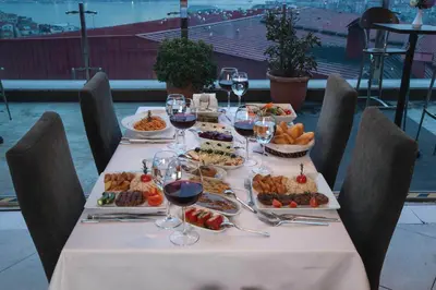 a table with plates of food and glasses of wine at Hotel Troya in Istanbul