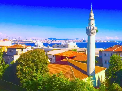 a white mosque with a tower on top of a city at Naz Wooden House Inn in Istanbul