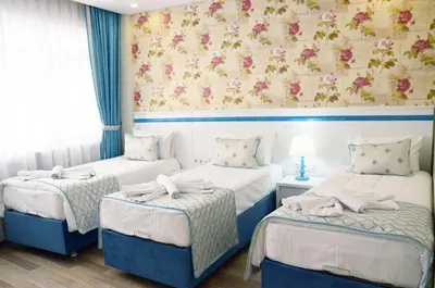 a bedroom with three beds and a wall with flowers at Star Holiday Hotel in Istanbul
