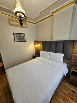 a bedroom with a large white bed with a black headboard at Gul Sultan Hotel in Istanbul