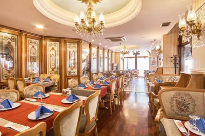 a restaurant with wooden tables and chairs and a chandelier at Best Western Empire Palace Hotel & Spa in Istanbul