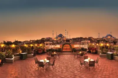 a patio with tables and chairs and a city at night at Armada Istanbul Old City Hotel in Istanbul