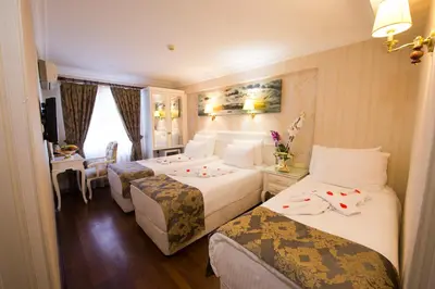 a hotel room with three beds and a desk at Golden Horn Hotel in Istanbul