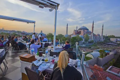 a group of people sitting at tables on a roof with a view of the h at Seven Hills Hotel - Special Category in Istanbul