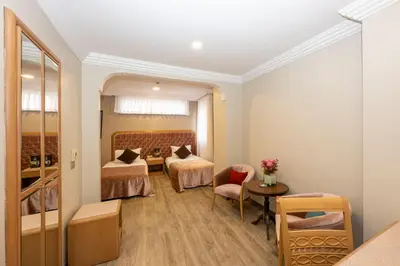 a room with two beds and a table and chairs at Grand Anka Hotel in Istanbul