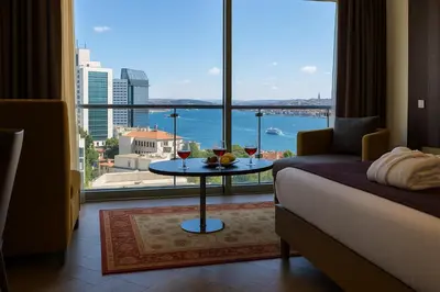 a room with a bed and a table with two glasses of wine at Taksim Gonen Hotel in Istanbul