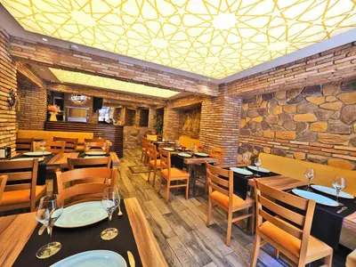 a restaurant with wooden tables and chairs and a stone wall at The Sunrise Hotel in Istanbul